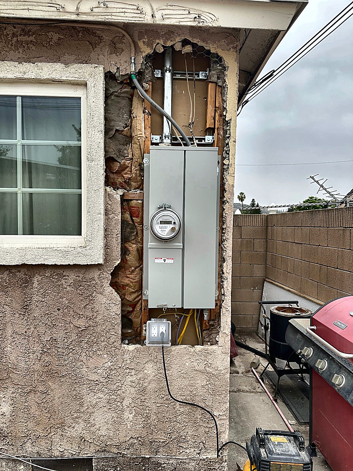 Meter opening on a pink stucco house